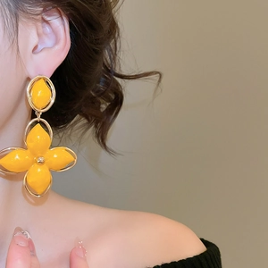Gros plan d'un mannequin portant des boucles d'oreilles fleurs jaunes rétro