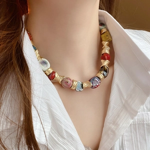 Close-up of ethnic ceramic flower necklace with colorful beads and gold metal accents
