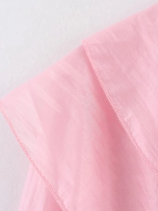 Détail macro des poignets à volants et coutures fines sur chemisier rose léger