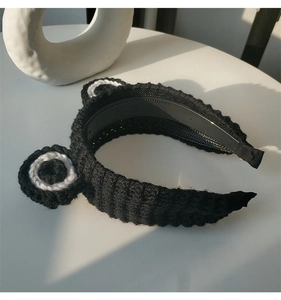 Close-up of black knitted headband featuring cute white and black panda ears design