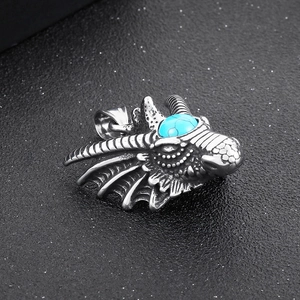 Close-up of a silver dragon head pendant with blue turquoise eyes in punk gothic style