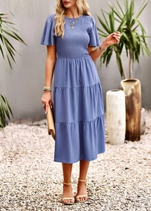 Blue smocked waist dress with tiered skirt and flutter sleeves on a professional model