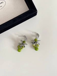 Close-up of silver flower earrings with green crystal grape tassels on a white background