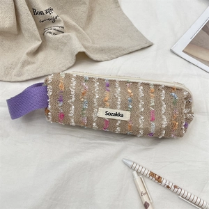 Detailed close-up of floral woven pencil case with purple handle and top zipper