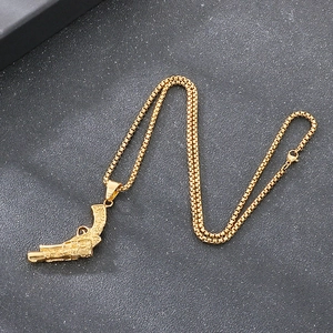 Macro view of gold pistol pendant with intricate engravings and box chain detail