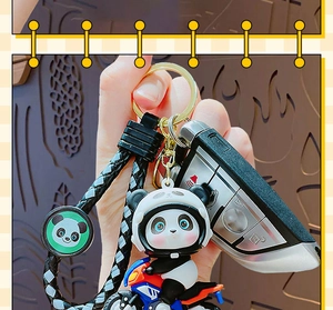 Close-up of a cute panda on a motorcycle keychain with woven strap and gold ring