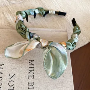 Cerchietto floreale chic con fiocco in seta verde su sfondo di libro decorativo