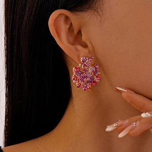 Close-up of a phoenix-shaped earring with pink and red crystal rhinestones on a female model