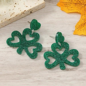 Detailed macro view of green glitter shamrock earrings on a rustic wood surface