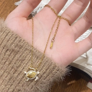 Detail of gold turtle pendant with hexagonal shell texture and sparkling zircon inlay