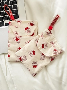 Detail of fabric stationery pouches featuring red cherry patterns and button closures
