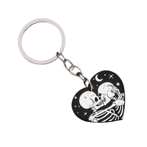 Gothic heart keychain featuring kissing skeletons with a moon and star pattern backdrop
