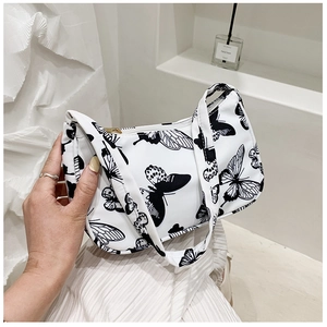 Detail of white shoulder bag featuring a black butterfly print and gold zipper hardware