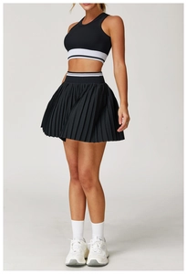 Detail of high-waisted black pleated tennis skirt with white stripe and matching crop top