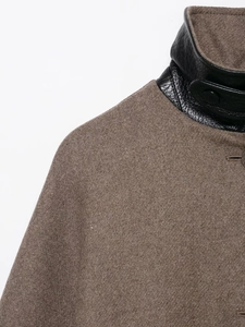 Dettaglio del cappotto marrone in lana con colletto alla coreana in pelle nera e bottone