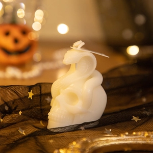 Detailed cream skull and snake candle on black mesh with festive bokeh background