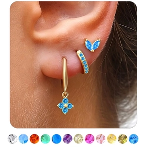 Detailed view of three-piece gold earring set with blue gemstones worn on the ear