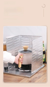 Close-up of heat-resistant silver aluminum foil oil splash guard around a cooking stove