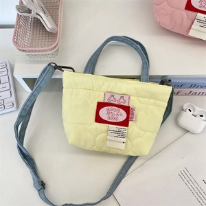 Détail du sac à main matelassé cœur jaune avec poignées bleues et patch cerise brodé