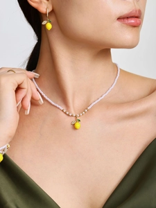 Dettaglio della collana di perle e orecchini al limone indossati da una modella