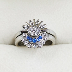 Close-up of celestial sun and moon rings with blue crystals on white velvet