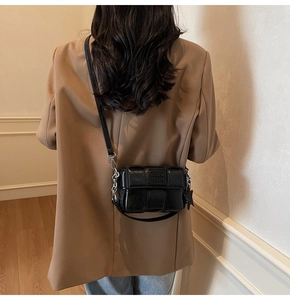 Détail du sac carré tressé noir avec breloque étoile et bandoulière en chaîne métallique