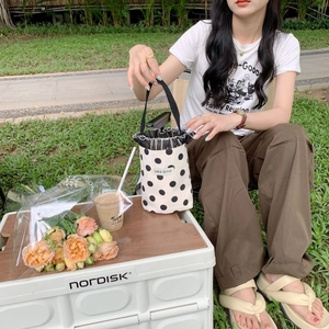 Polka dot canvas mini bucket bag with black gauze trim in a relaxed outdoor setting