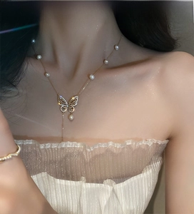 Detail of gold butterfly necklace with zircon crystals and freshwater pearls on model