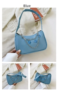 Detail of light blue underarm bag with double silver chains and butterfly charms
