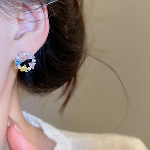 Detail of a floral wreath stud earring featuring heart gemstones and pearls on ear