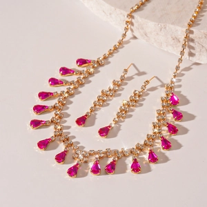 Detailed close-up of gold jewelry set with pink teardrop crystals and sparking diamonds