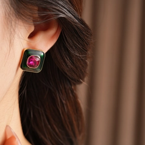 Close-up of vintage square earrings with dark green frame and red gemstone detail