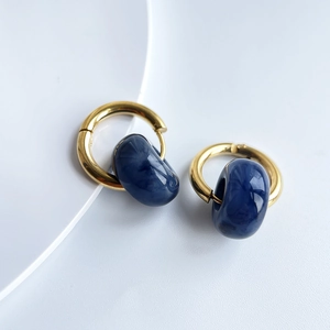 Detailed shot of 18k gold earrings featuring deep blue marble texture resin charms