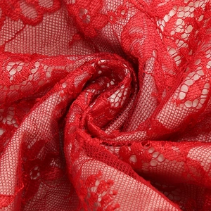 Macro detail of elegant red floral lace fabric with intricate mesh texture and ruffles