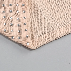 Detail view of sheer mesh fabric with shimmering silver rhinestones on a beige party dress