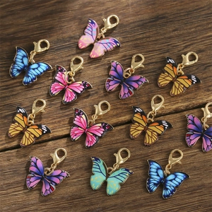 Close-up of colorful butterfly alloy pendants with golden lobster clasps on wood