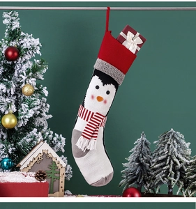 Detailed close-up of a knitted Christmas stocking with cute cartoon penguin and striped scarf