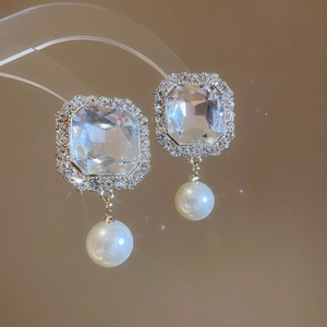 Detailed close-up of vintage square rhinestone earrings with white pearls on a display