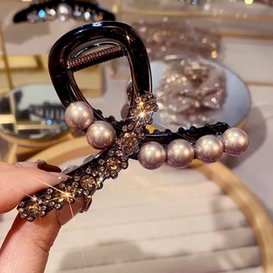 Close-up of tortoise shell hair claw clip with elegant pearls and shimmering rhinestones