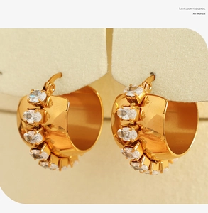 Macro detail of 18K gold plated C-shaped earrings with oval cubic zirconia inlay