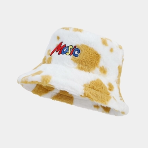 Close-up of plush cow print bucket hat with colorful Music letter embroidery detail