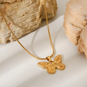 Elegant 18K gold plated stainless steel necklace with a hollow butterfly pendant on rock