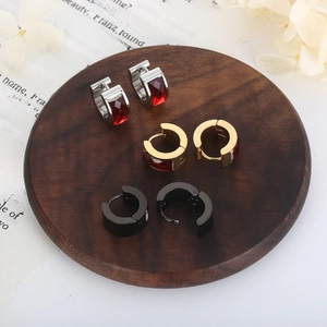Macro view of stainless steel hoop earrings in silver, gold, and black with red gemstones