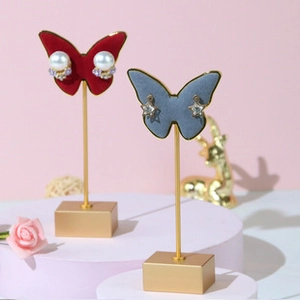 Detail of red and blue butterfly velvet earring stands with gold metal base