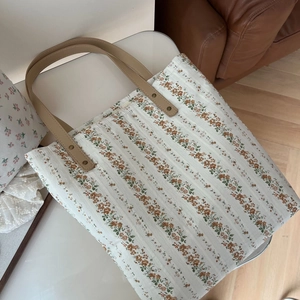 Détail du sac fourre-tout à fleurs avec anses en cuir marron et rivets vintage