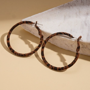 Macro detail of leopard print fabric texture on classic large hoop fashion earrings