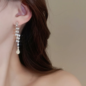 Close-up of silver rhinestone tassel earrings with pear-shaped drops on a female model