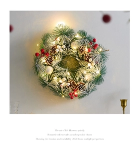 Close-up of pine needle wreath with pinecones, red berries and warm LED lights