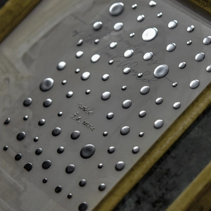 Macro shot of silver metallic dot nail stickers featuring a high-gloss 3D textured finish