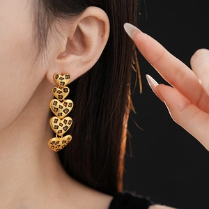 Close-up of model wearing heart-shaped leopard print dangle earrings in a golden finish